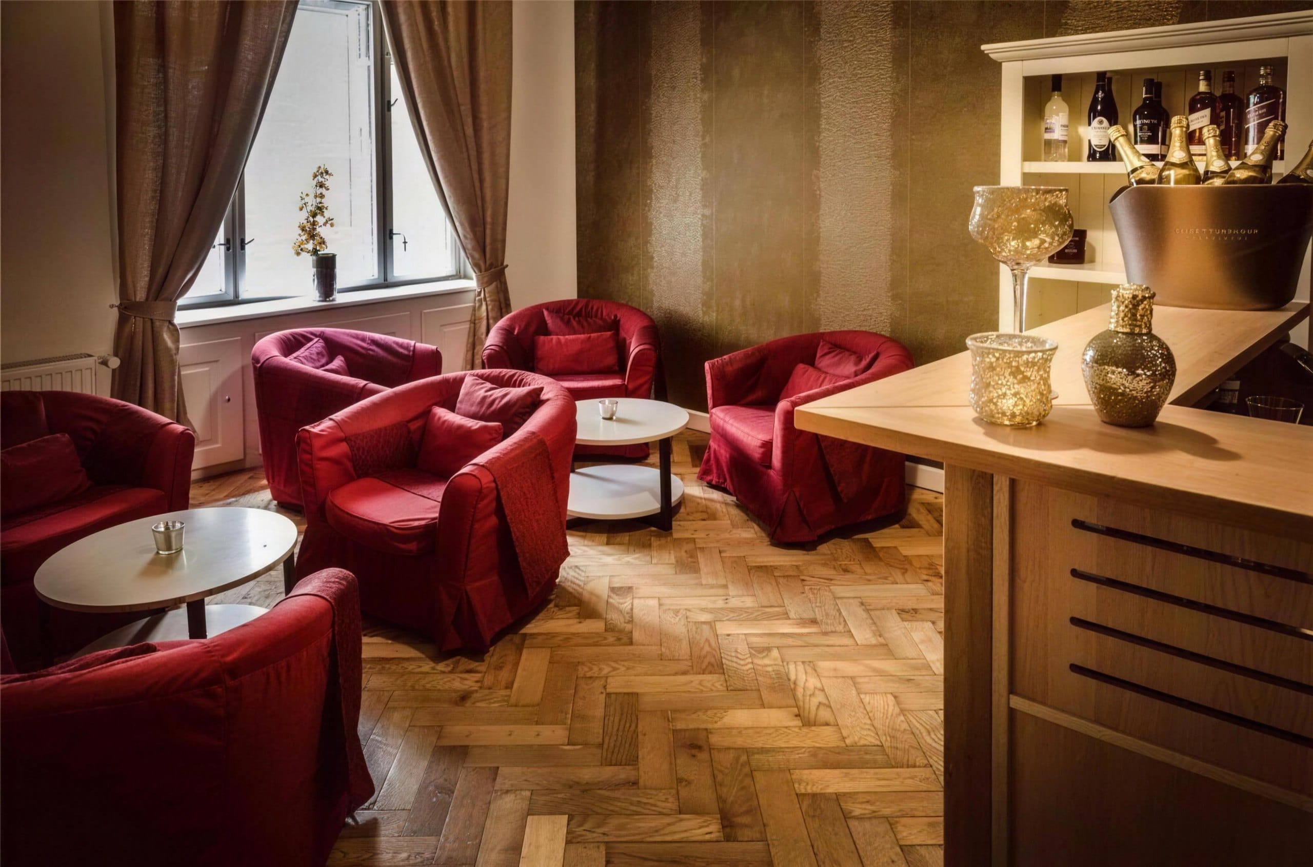 Lounge with red armchairs and a bar at Imperial salon in Prague